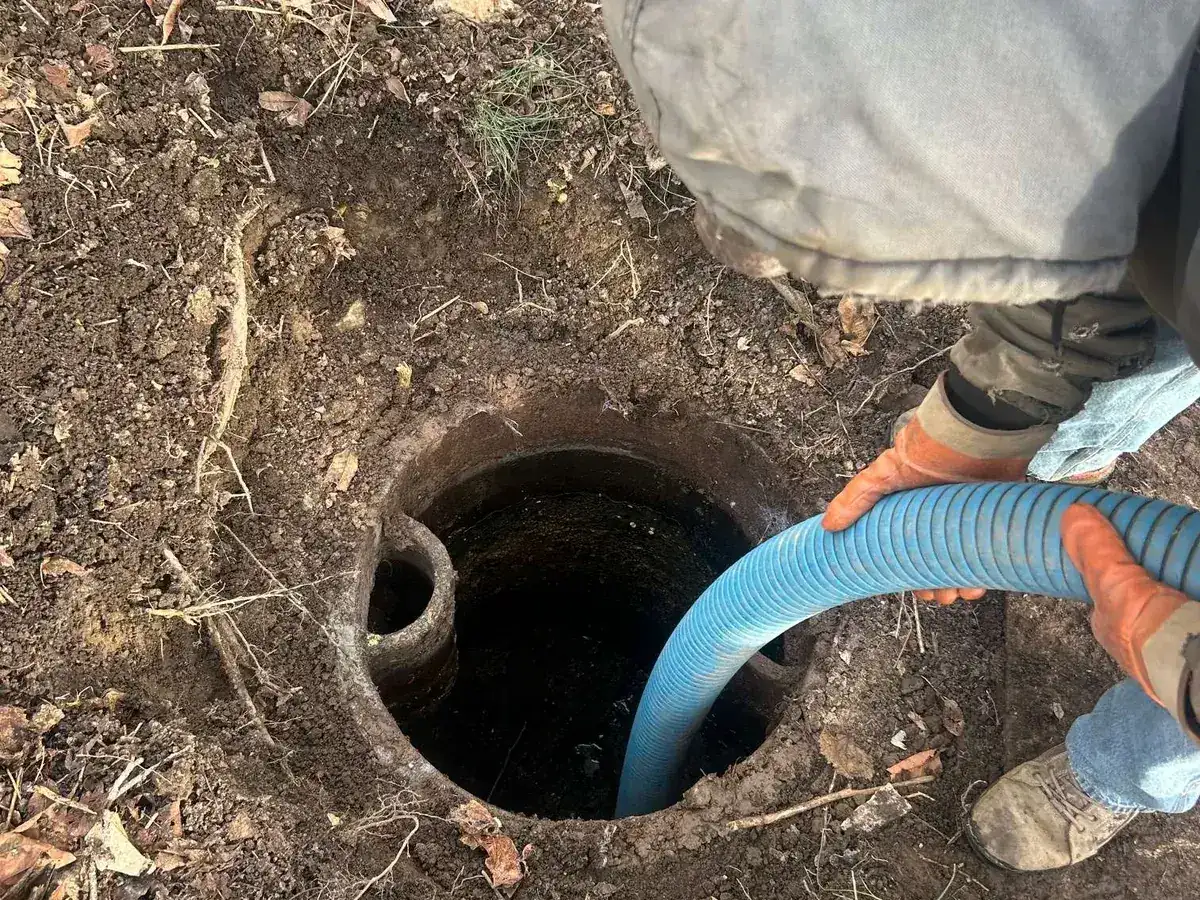 A suction hose lowered into an open septic tank access during an emergency call